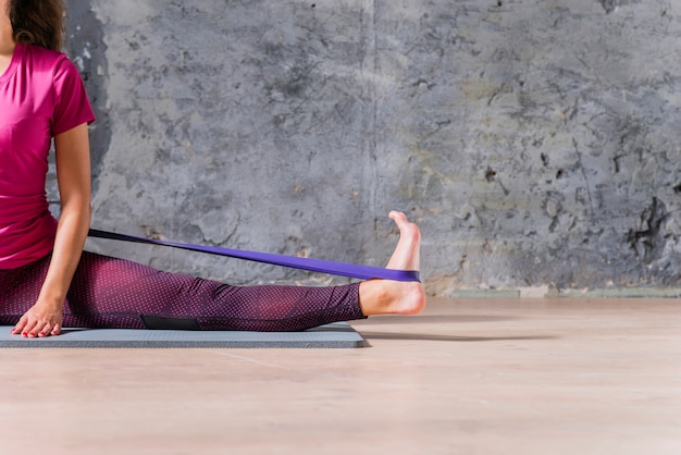 Foto modelo de fitness feminino fazendo exercícios de alongamento com banda de resistência