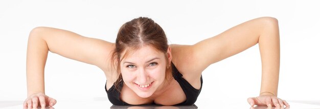 Modelo de fitness feminino se exercitando em estúdio com pesos dunbell e fazendo uma rotina de alongamentos e elevadores no chão