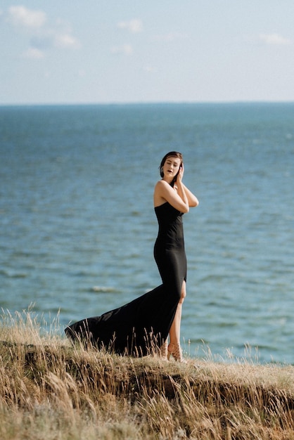 Foto modelo de garota alta em um vestido preto nas colinas da montanha