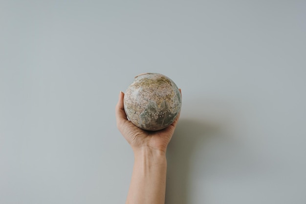 Modelo de globo na mão feminina sobre fundo azul Salve o conceito de planeta Terra do mundo Direitos das mulheres e conceito de poder