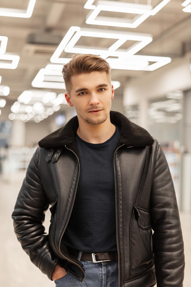 Foto modelo de hipster de homem brutal bonito com penteado em uma elegante jaqueta de couro preta caminha no shopping