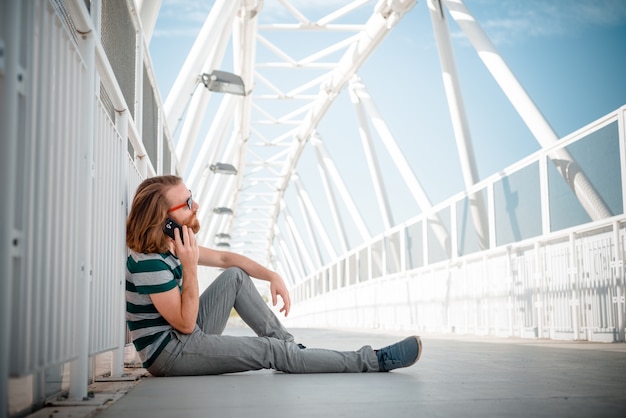 modelo de hipster elegante com cabelo vermelho longo e estilo de vida da barba no telefone