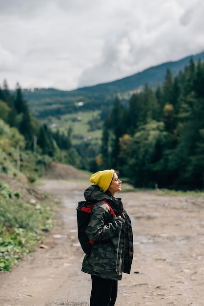 Foto modelo de hipster feminino saudável ativo caminhando ao longo da estrada da montanha da floresta