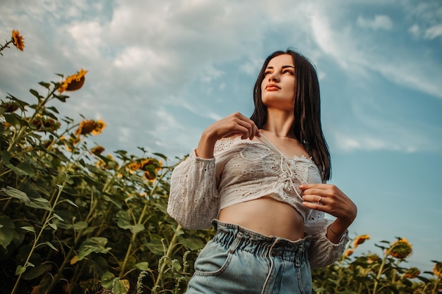 Modelo de linda jovem caminha pelo buquê amarelo florescendo campo de girassol ao ar livre pôr do sol