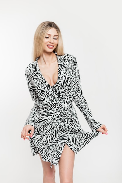 Modelo de linda jovem loira feliz com um sorriso com um corpo sexy em um vestido estampado de zebra em um fundo branco no estúdio
