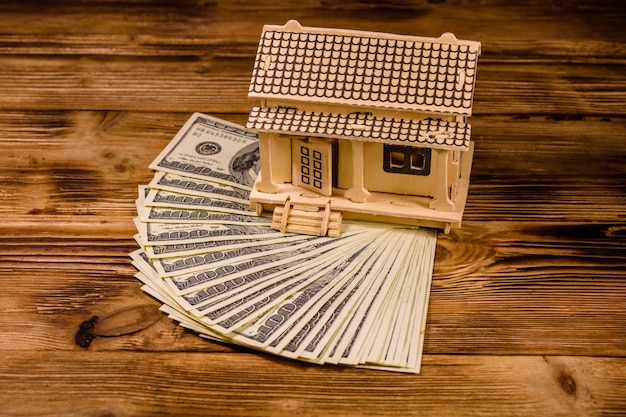 Modelo de madeira compensada da casa e notas de cem dólares Conceito imobiliário de empréstimo