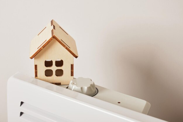 Modelo de madeira de uma casa em um radiador elétrico para aquecer a casa, copie o espaço, usando o aquecedor no conceito de estação fria
