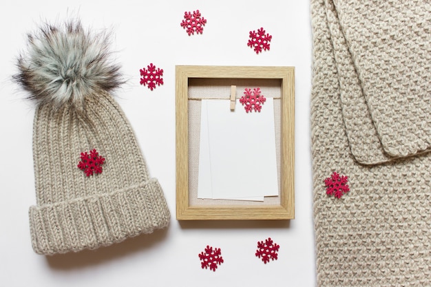 Foto modelo de maquete de natal com chapéu e lenço de malha, moldura de madeira e muitos flocos de neve de madeira vermelhos.