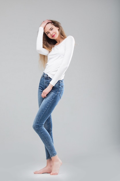 Modelo de menina bonita em jeans skinny e top no estúdio em fundo branco