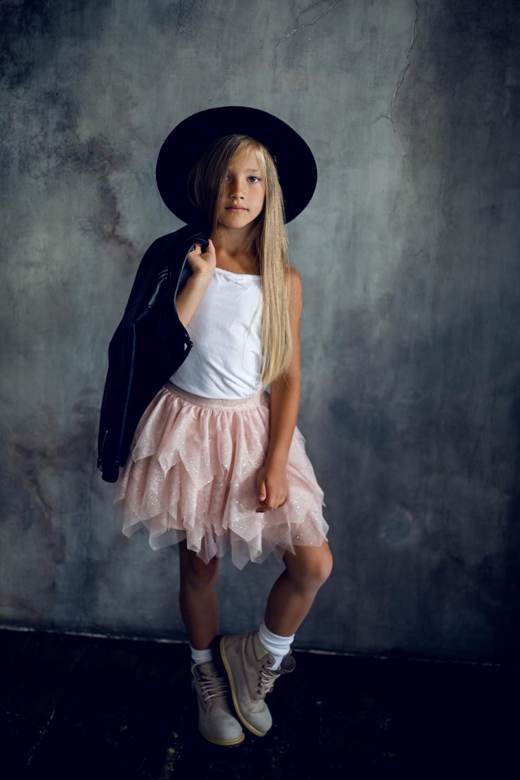 Foto modelo de menina de moda com saia de casaco de couro e sapatos de pé contra a parede no estúdio