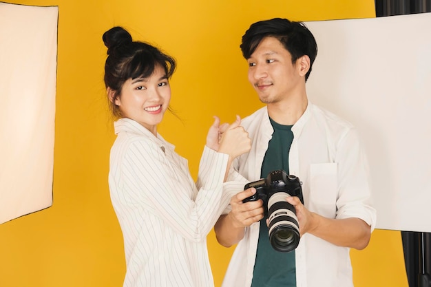 Modelo de moda e fotógrafo de pé contra o fundo