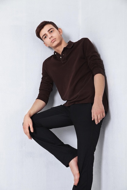 Modelo de moda masculina jovem posando com uma roupa casual em fundo cinza