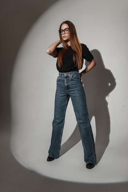 Modelo de moda mulher bonita com roupa elegante com jeans de camiseta preta e sapatos em estúdio