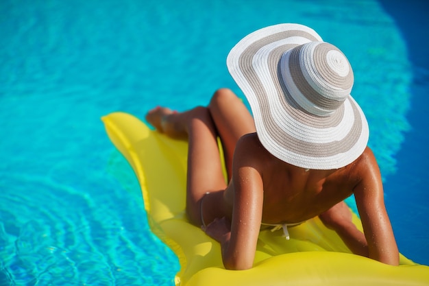 Modelo de mulher bonita e sexy de biquíni relaxando na piscina