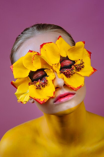 modelo de mulher com flores amarelas ao redor dos olhos. O corpo da mulher é pintado de amarelo