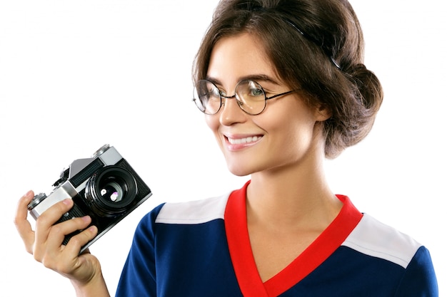 Modelo de mulher em look vintage, segurando a câmera retro nas mãos