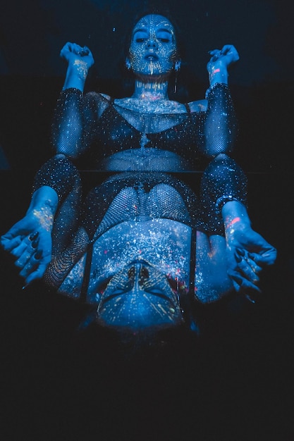 Modelo de mulher em luz neon linda modelo menina com design artístico de maquiagem fluorescente Foto matizada azul Conceito de foto marinha Cosplay avatar