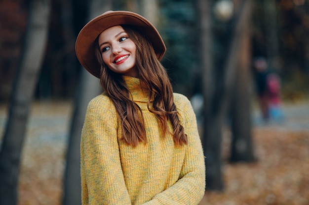 Modelo de mulher jovem no parque outono com folhas de plátano de folhagem amarela. Moda de outono.