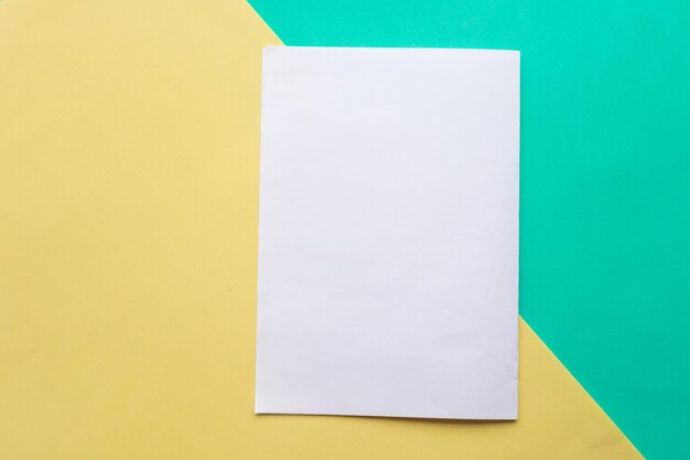 Foto modelo de papel branco em branco em fundo de papel geométrico verde e amarelo conceito mínimo