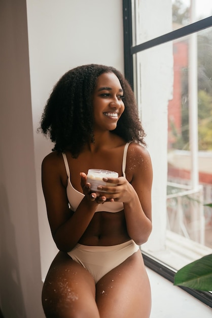 Foto modelo de pele negra vestido de cueca segura uma jarra com um esfoliante