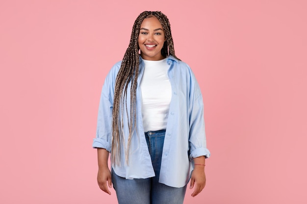 Modelo de senhora obesa muito afro-americana em pé no fundo rosa