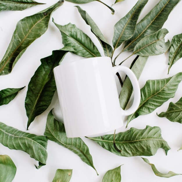 Modelo em branco de caneca branca e folhas verdes