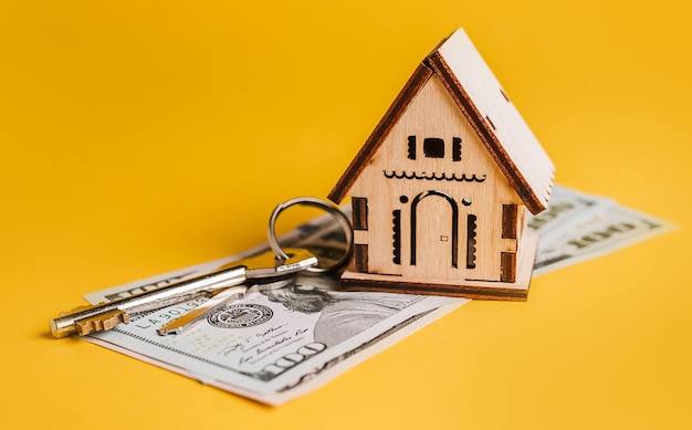 Modelo em miniatura da casa, chaves e dinheiro em um fundo amarelo. investimento, imobiliário, casa, habitação