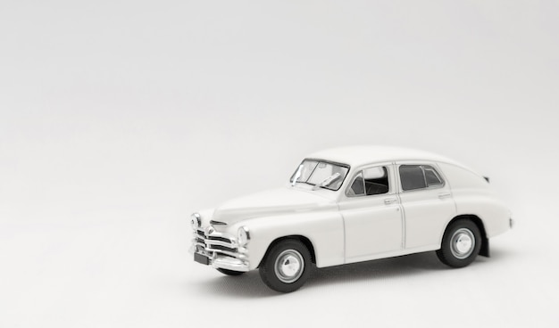 Foto modelo em miniatura de um carro retrô de brinquedo branco sobre um fundo branco.