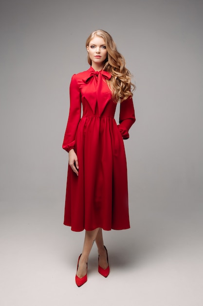 Modelo esbelto deslumbrante em vestido vermelho brilhante e salto preto.