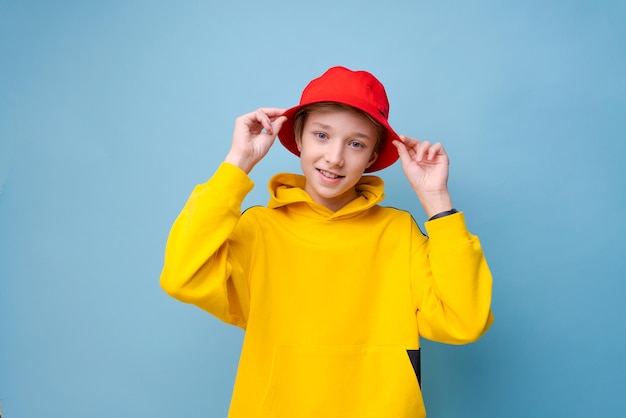 Modelo de estilo de ciudad de rapero disparando a un tipo hipster feliz con sudadera amarilla y sombrero rojo aislado ba azul