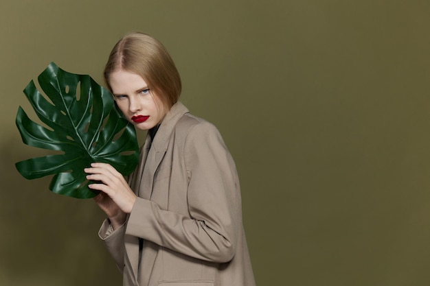 Modelo de estudio de maquillaje brillante con abrigo de hoja de palma verde de mujer bonita inalterado