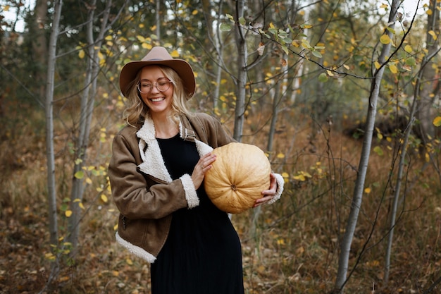 Modelo feliz en otoño de sombrero y calabaza