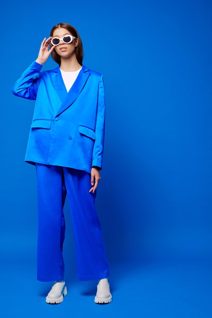Foto modelo femenino asiático de moda con traje azul botas blancas y gafas de sol