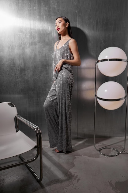 Modelo femenino asiático de moda en traje de brillo plateado metálico