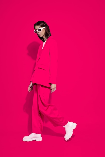 Foto modelo femenino asiático de moda con traje rosa botas blancas y gafas de sol