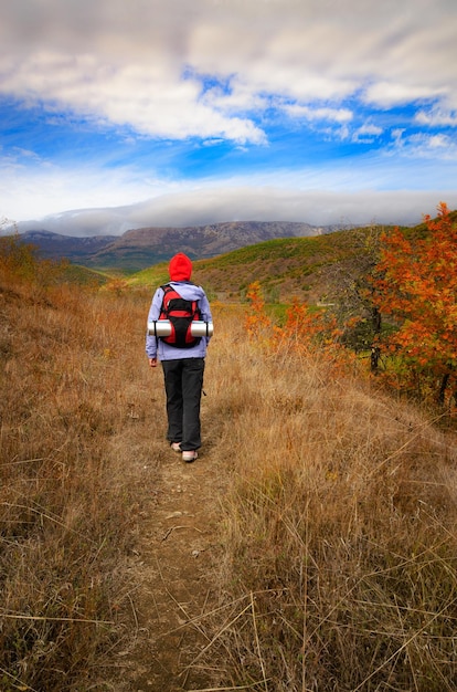 Modelo femenino caucásico activo de mediana edad con mochila caminando en las montañas en otoño