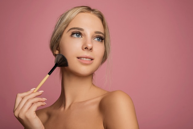 Foto modelo femenino con pincel de maquillaje