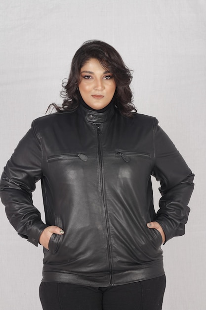 Un modelo femenino de tamaño grande posando con chaqueta de cuero negra y camiseta