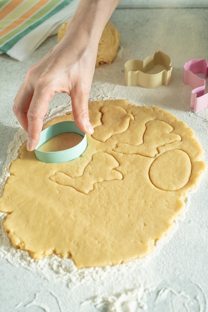 Modelo feminino corta massa com cortador de biscoitos na mesa da cozinha