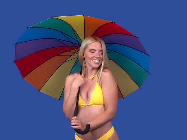 Modelo feminino de conteúdo em biquíni segurando guarda-chuva vívido