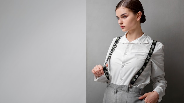 Foto modelo feminino elegante em elegante camisa branca e suspensórios. novo conceito de feminilidade