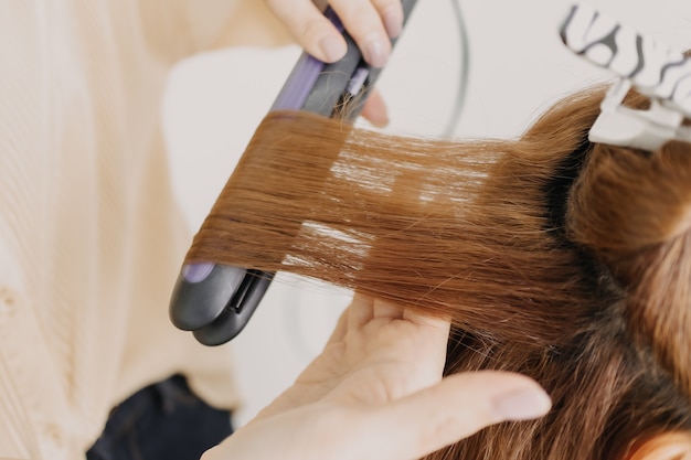 Modelo feminino está penteando o cabelo pelo cabeleireiro na sala de estúdio