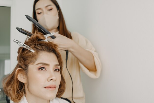 Modelo feminino está penteando o cabelo pelo cabeleireiro na sala de estúdio