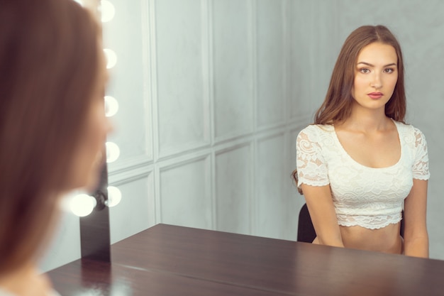 Modelo feminino jovem sentado no banquinho antes da sessão de fotos