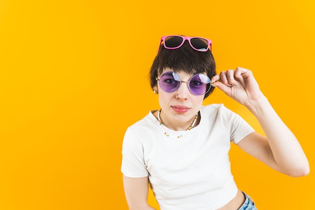 Modelo feminino olhando diretamente para a câmera através de um par de óculos de sol e usando outro par