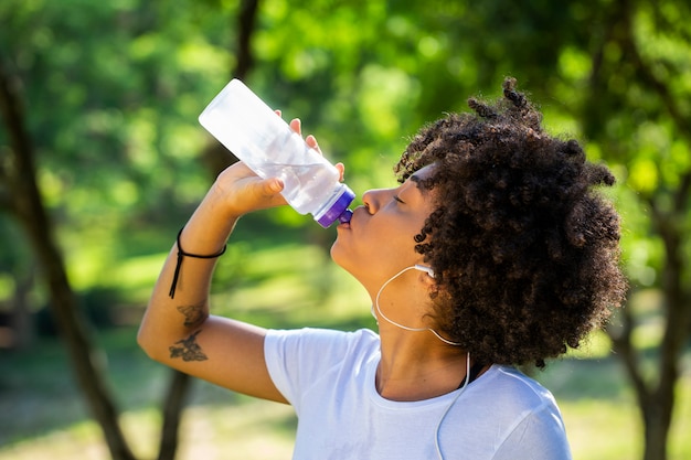 Modelo de fitness con una botella de agua en el parque