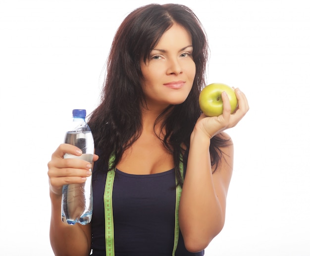 Modelo de fitness femenino sosteniendo una botella de agua y manzana verde