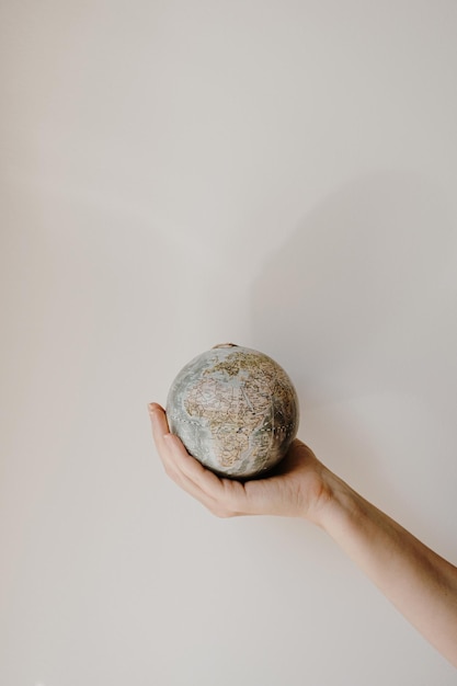 Modelo de globo en mano femenina sobre fondo blanco Salvar el mundo planeta Tierra concepto Derechos de la mujer y concepto de poder