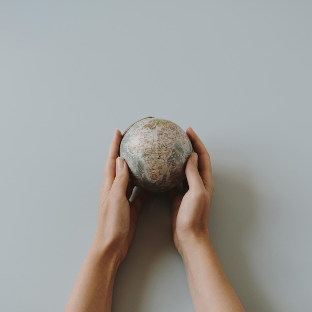 Modelo de globo en manos femeninas sobre fondo azul Salvar el mundo planeta Tierra concepto Derechos de la mujer y concepto de poder