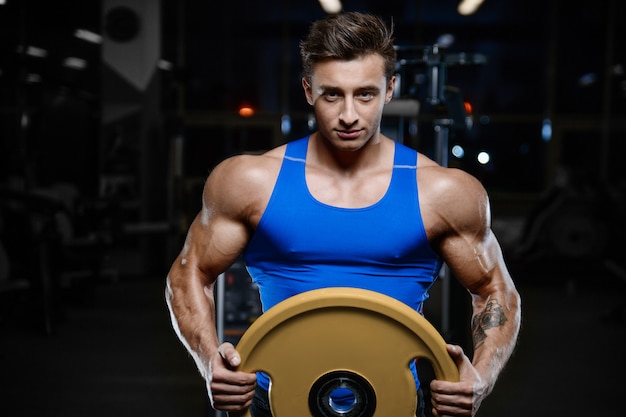 Modelo guapo joven entrenamiento en gimnasio